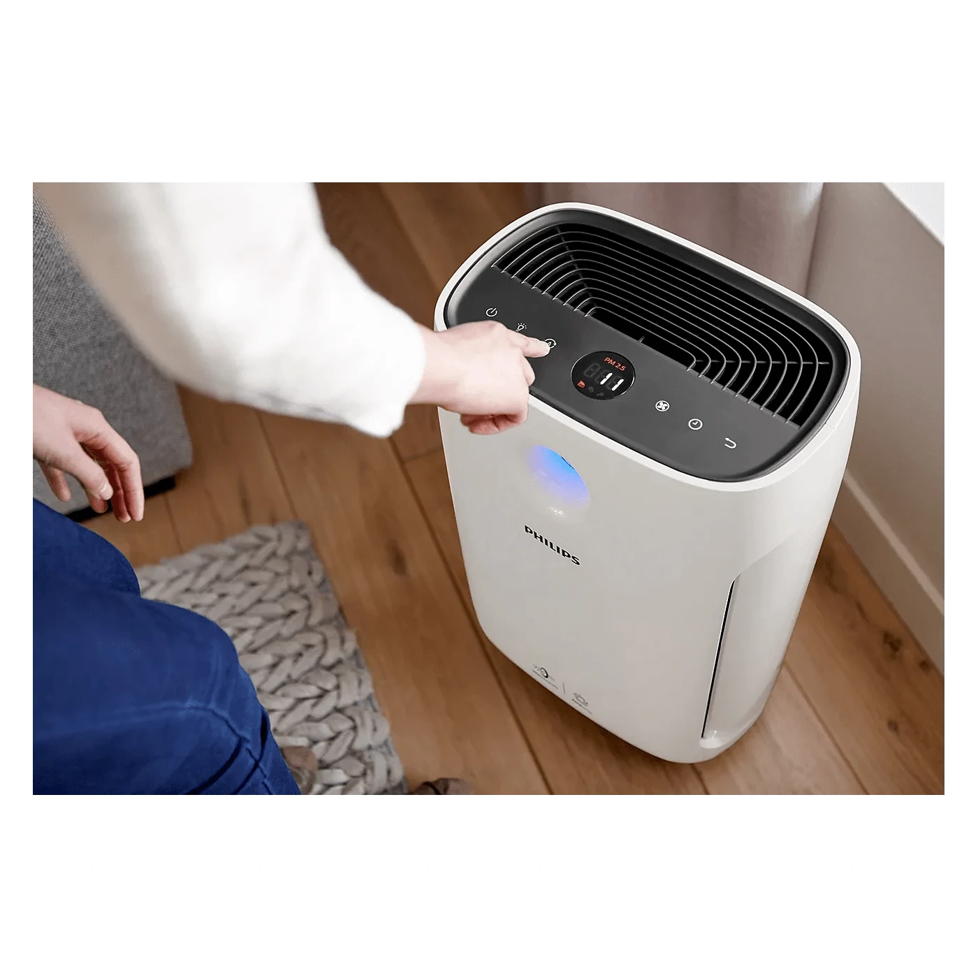 Hand adjusting Philips AC2887/20 touch controls with PM2.5 reading displayed