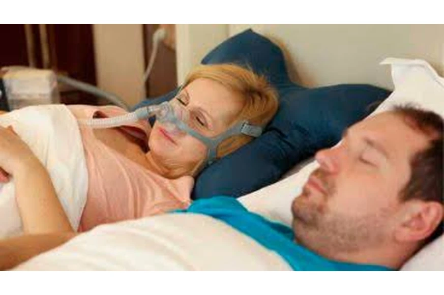 Couple in bed, woman wearing BMC N5A nasal mask, man sleeping beside her
