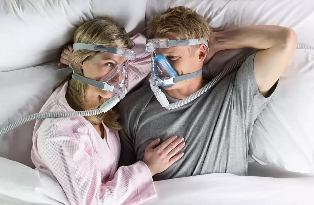 Couple in bed, one wearing the Philips Amara Silicone full face CPAP mask