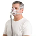 Man wearing ResMed AirFit F20 full face mask, front-angled side view, white t-shirt, white background