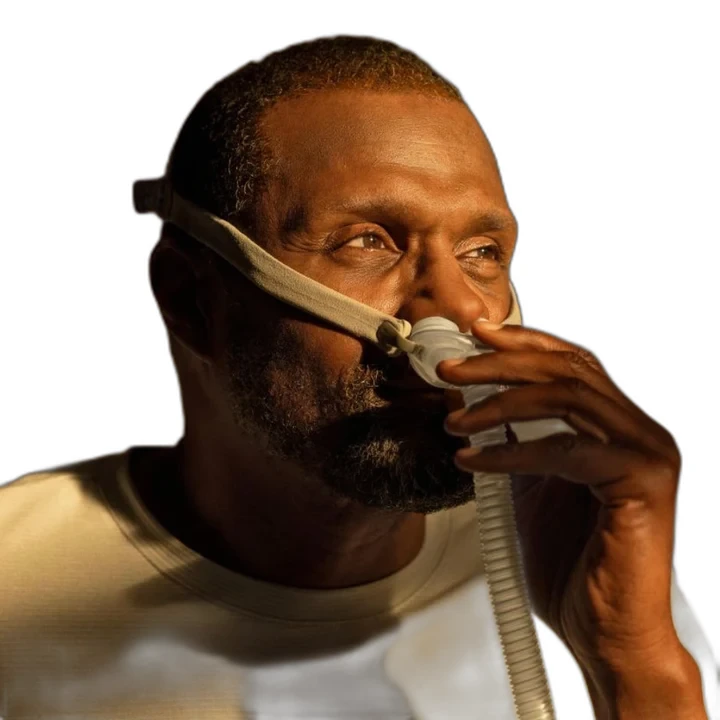 Man wearing ResMed AirFit P10 for AirMini nasal pillow mask, side profile, holding tubing