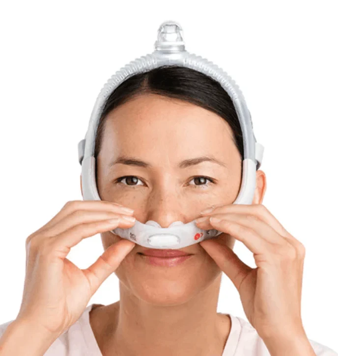 Woman fitting the ResMed AirFit P30i nasal pillow mask on her face